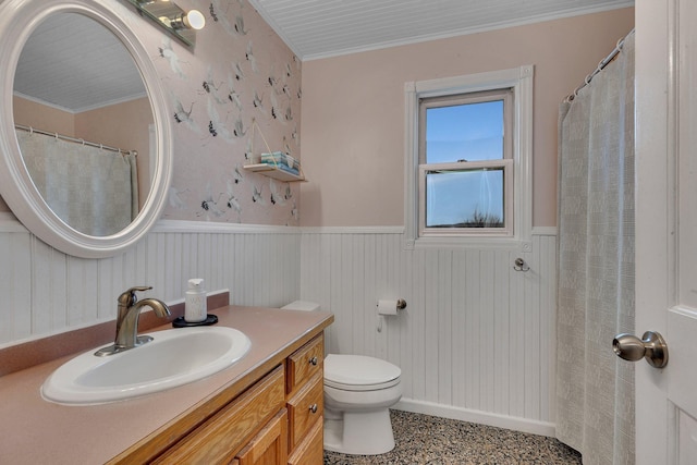 bathroom with a wainscoted wall, toilet, vanity, and crown molding