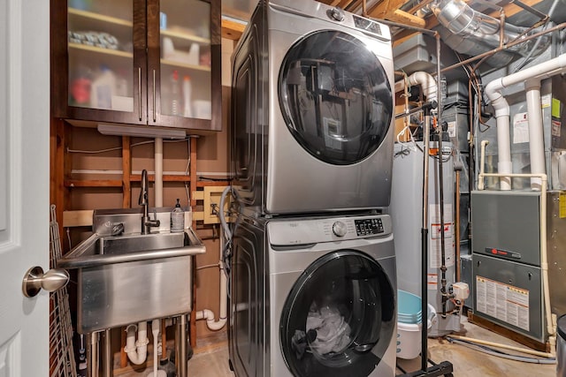 washroom featuring stacked washer and dryer, laundry area, heating unit, water heater, and a sink