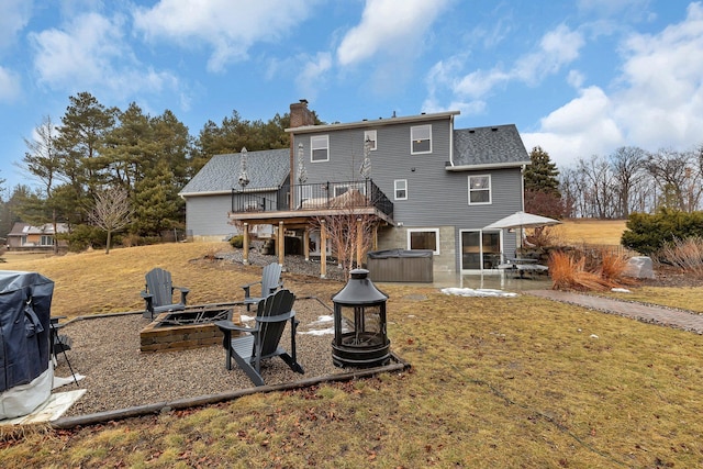 back of house with a hot tub, an outdoor fire pit, a chimney, and a patio