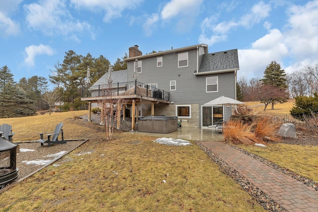 back of house with a chimney, a patio, a hot tub, and a lawn