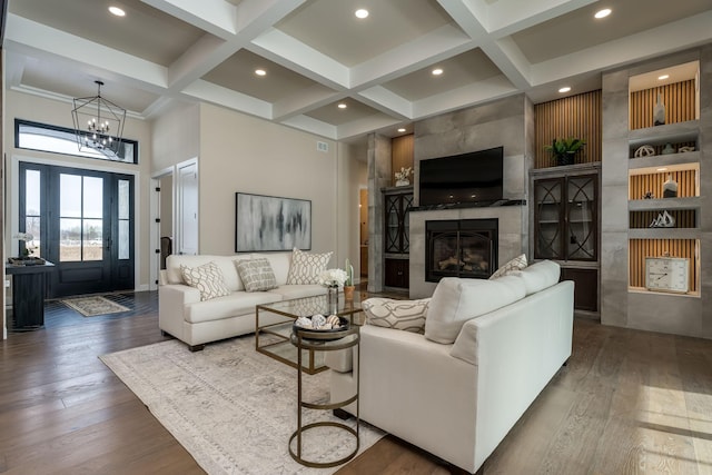 living room featuring beam ceiling, wood finished floors, coffered ceiling, and a premium fireplace