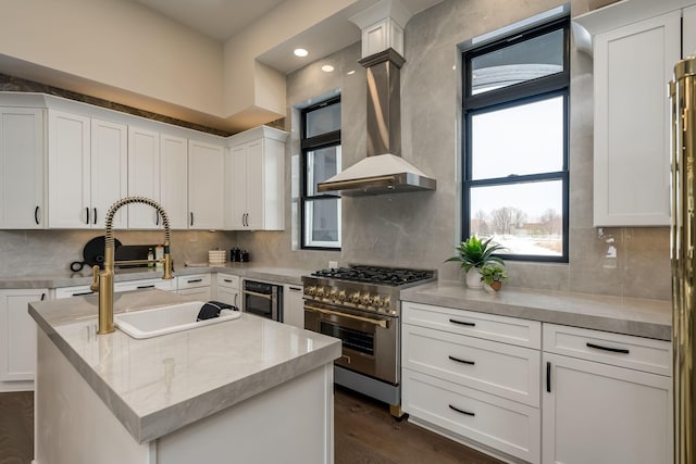 kitchen featuring a center island, range hood, white cabinetry, high end stainless steel range, and a sink