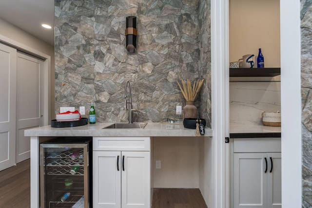 bar with beverage cooler, a sink, tasteful backsplash, wood finished floors, and indoor wet bar