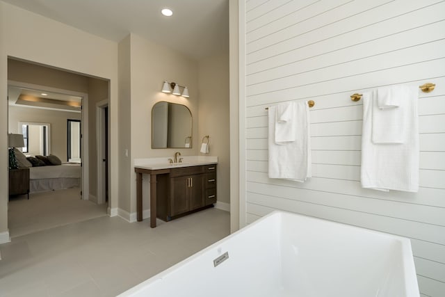 bathroom featuring recessed lighting, connected bathroom, baseboards, a freestanding bath, and vanity