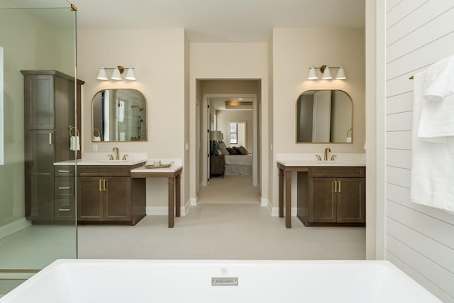 full bath featuring a sink, a soaking tub, two vanities, and ensuite bathroom