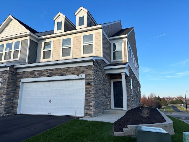 view of front facade with an attached garage, stone siding, and aphalt driveway