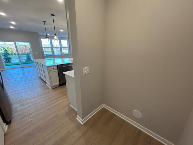 kitchen featuring dishwasher, light countertops, light wood-style flooring, and white cabinetry