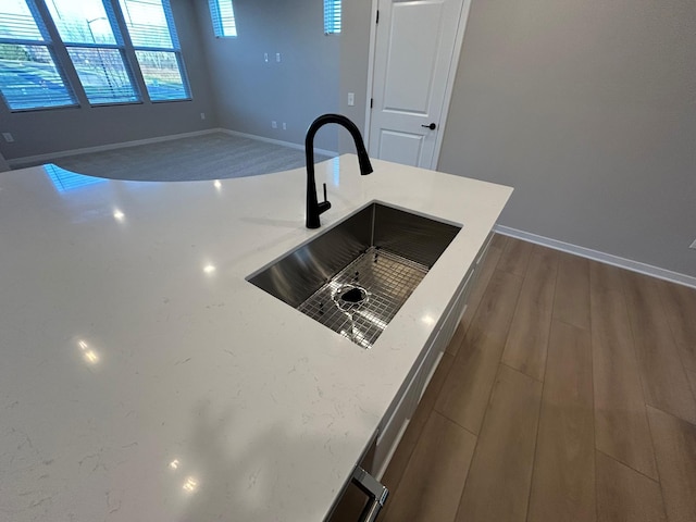 interior details featuring light stone counters, baseboards, dark wood-style flooring, and a sink