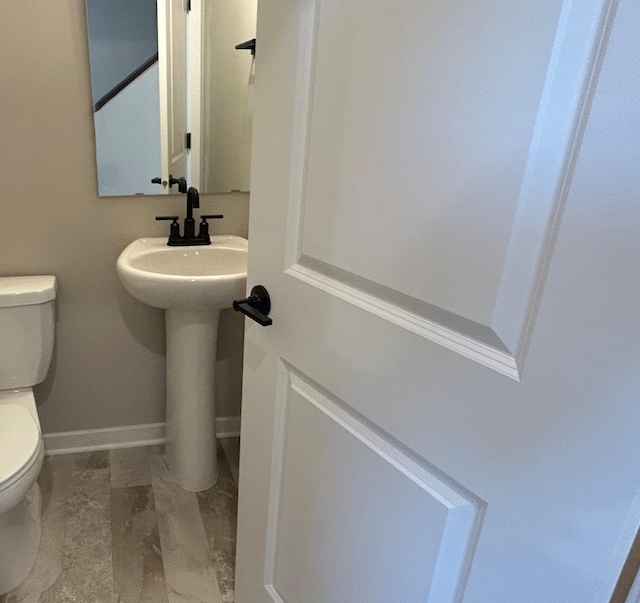 bathroom with toilet, baseboards, and a sink