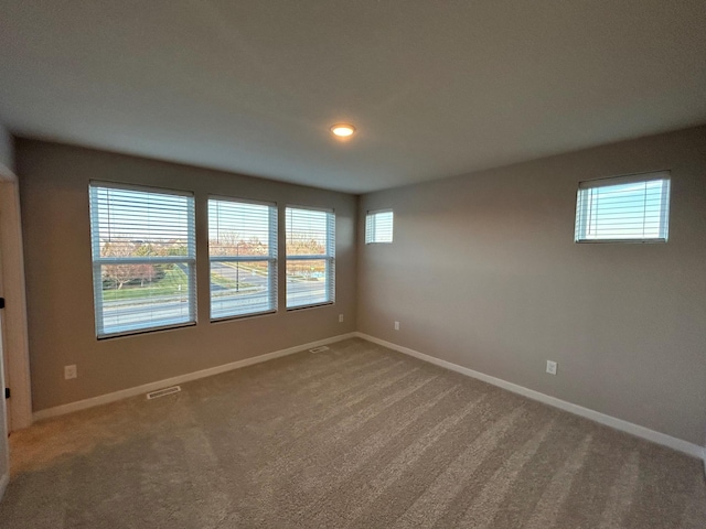 carpeted empty room featuring visible vents and baseboards