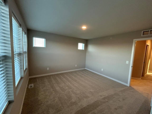 spare room with carpet flooring, visible vents, and baseboards