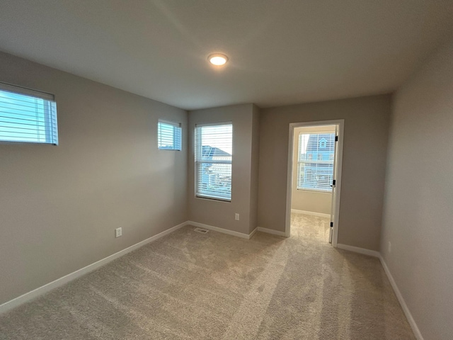 unfurnished room with light carpet and baseboards