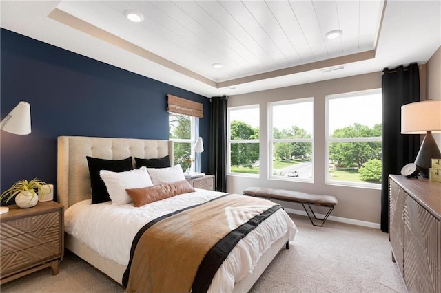 bedroom with light carpet, multiple windows, baseboards, and a raised ceiling