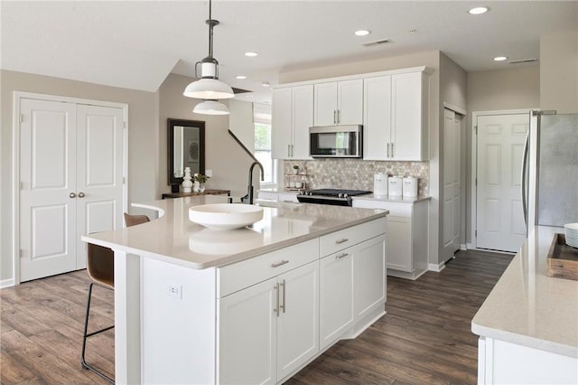 kitchen with visible vents, a breakfast bar, stainless steel appliances, light countertops, and a sink