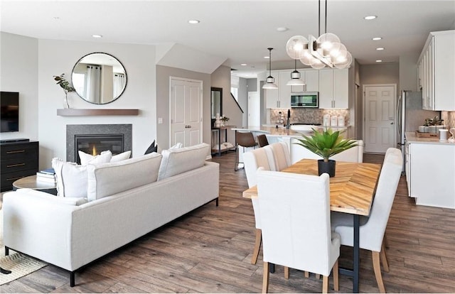 dining area featuring recessed lighting, dark wood-type flooring, and a glass covered fireplace