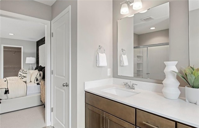 bathroom featuring a shower with door, visible vents, a walk in closet, and vanity