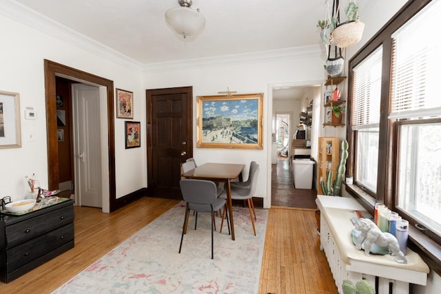 dining area featuring light wood-style floors, baseboards, and crown molding