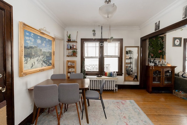 dining room featuring radiator, crown molding, and wood finished floors