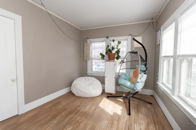 sitting room featuring baseboards, crown molding, and wood finished floors