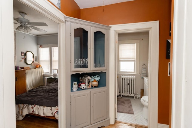 bedroom featuring crown molding, light wood finished floors, and radiator