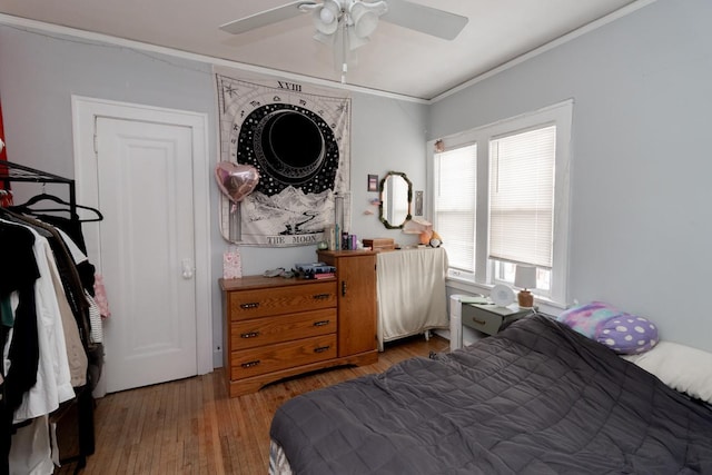 bedroom with crown molding, ceiling fan, and wood finished floors