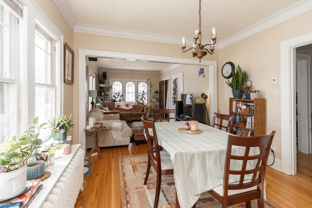 dining space with light wood-type flooring, a chandelier, and crown molding