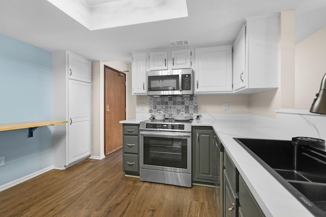 kitchen with visible vents, gray cabinetry, dark wood-style floors, white cabinets, and stainless steel appliances