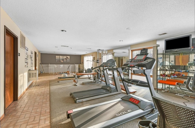 exercise room featuring brick floor, visible vents, and a textured ceiling