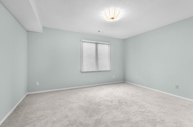 empty room with visible vents, baseboards, carpet, and a textured ceiling