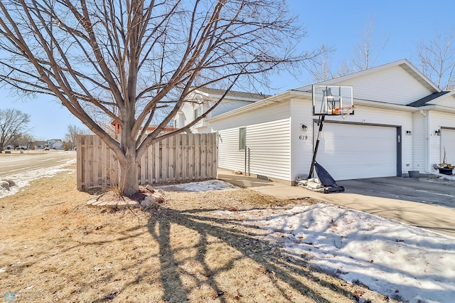 view of side of home with a garage, driveway, and fence