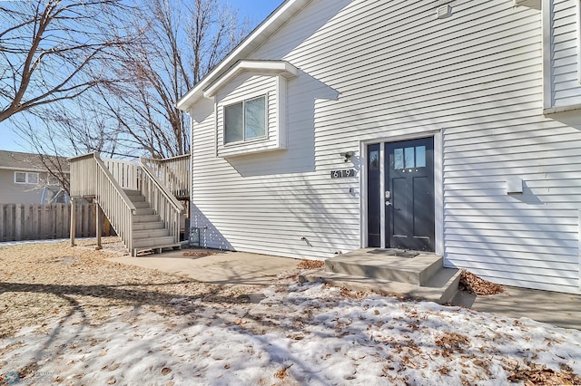 view of exterior entry with a patio area and fence