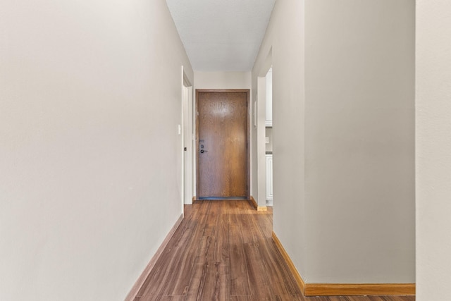 corridor with dark wood-style floors and baseboards