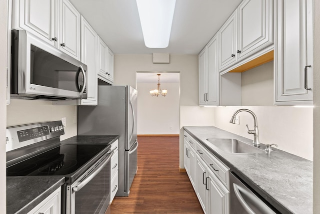 kitchen with dark wood-type flooring, a sink, white cabinetry, stainless steel appliances, and a chandelier