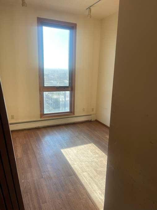 unfurnished room with baseboard heating and wood finished floors