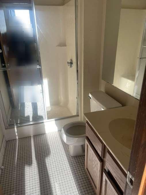 full bathroom featuring tile patterned flooring, a stall shower, toilet, and vanity