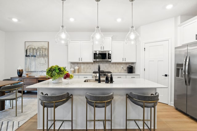 kitchen featuring stainless steel appliances, a breakfast bar, backsplash, and white cabinets