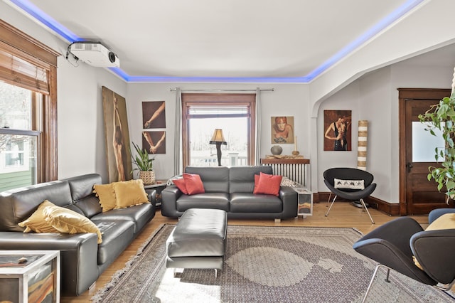 living room featuring a wall mounted air conditioner, baseboards, and wood finished floors