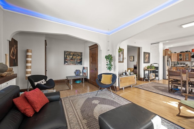 living area featuring arched walkways and light wood-type flooring