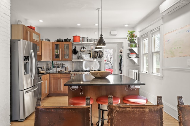 kitchen with an AC wall unit, dark countertops, stainless steel refrigerator with ice dispenser, and a healthy amount of sunlight