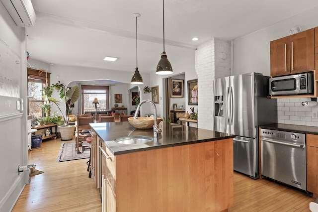 kitchen featuring backsplash, a wall unit AC, light wood-style floors, stainless steel appliances, and a sink