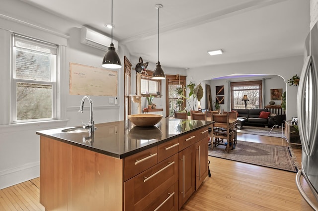 kitchen with light wood-type flooring, a wall mounted AC, a sink, dark countertops, and freestanding refrigerator