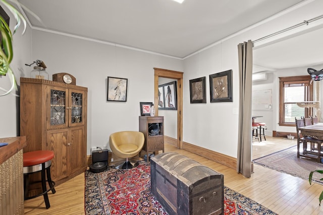 living area with light wood finished floors, a wall mounted AC, crown molding, and baseboards