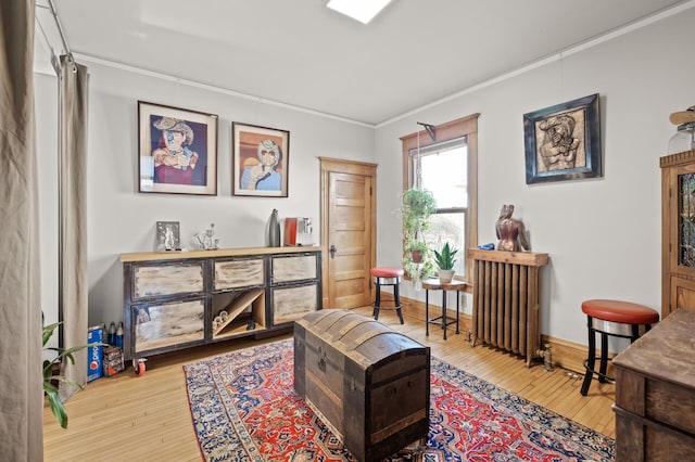 living area featuring hardwood / wood-style floors, crown molding, radiator heating unit, and baseboards