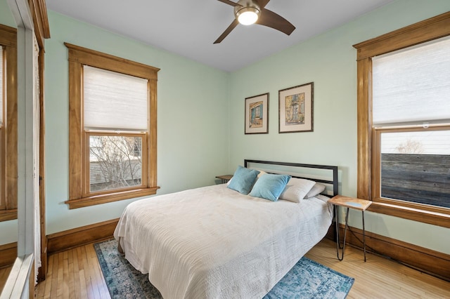 bedroom with multiple windows, ceiling fan, baseboards, and wood-type flooring