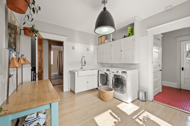 laundry area with a sink, light wood-style flooring, cabinet space, and washing machine and dryer