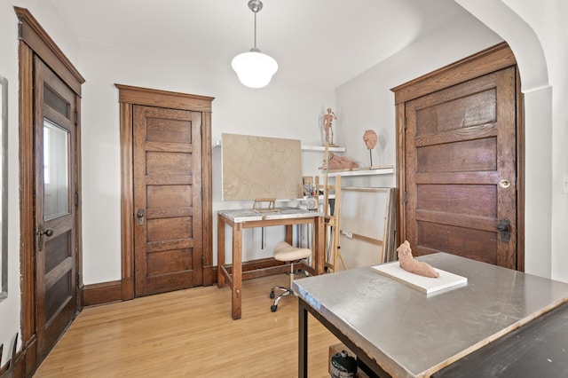 office with light wood-type flooring, arched walkways, and baseboards