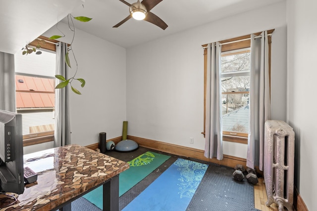 exercise area featuring baseboards, radiator, and ceiling fan