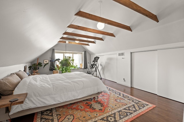 bedroom with visible vents, two closets, wood finished floors, and vaulted ceiling with beams