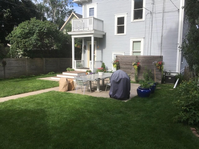 back of property featuring a patio area, a balcony, a yard, and fence