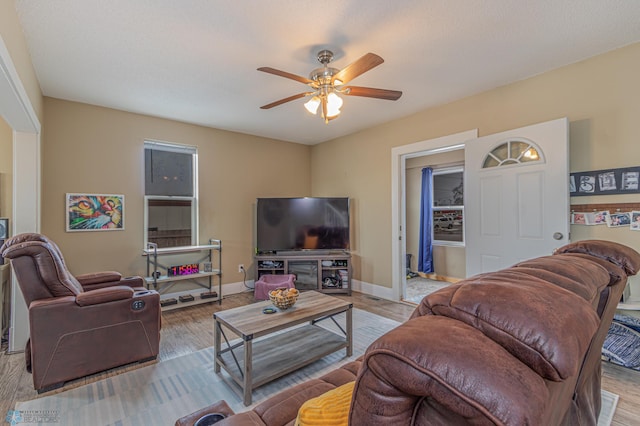 living area featuring wood finished floors, baseboards, and ceiling fan